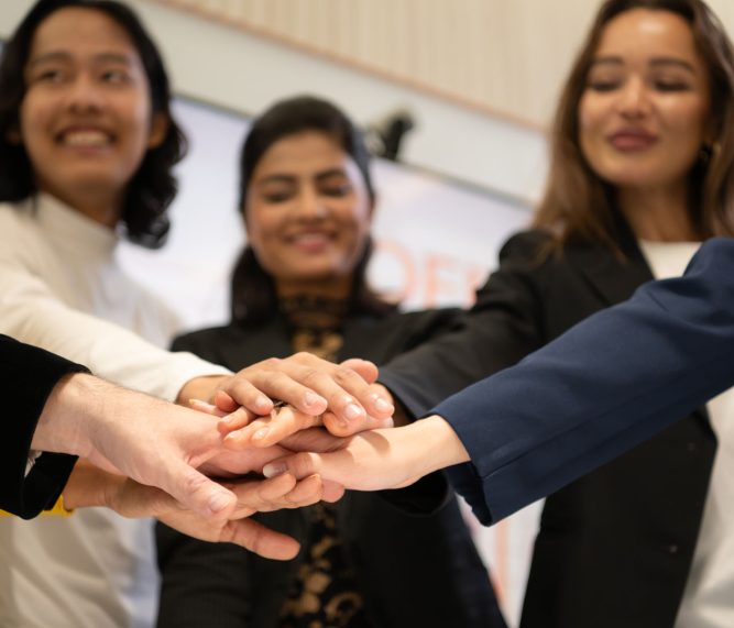 Business people putting their hands together as a symbol of unity and teamwork