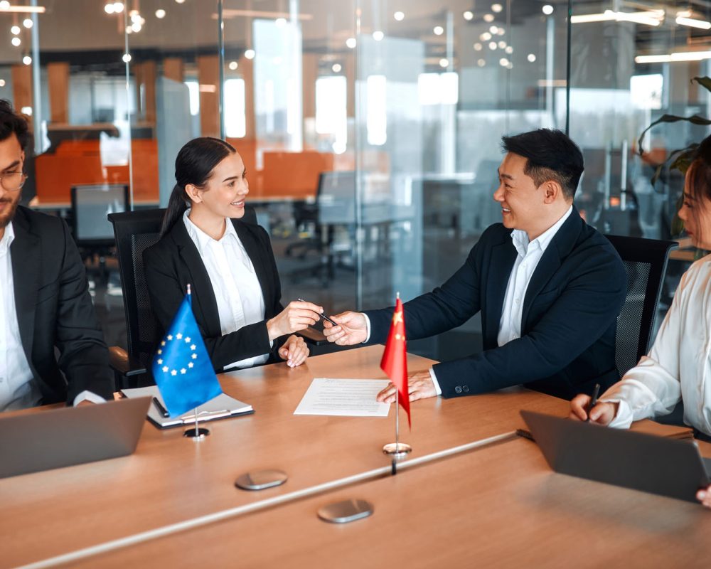 The flags of China and the European Union are on the table during negotiations between diplomats and businessmen. Representatives discuss relations between countries, signing a treaty.